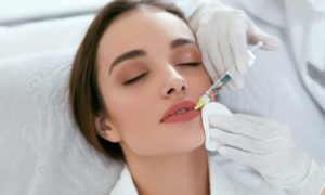 Woman getting dermal filler injection in lip