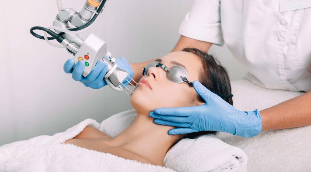 Female patient receiving laser treatment on face