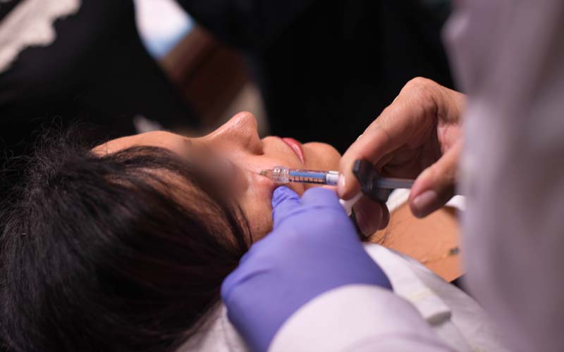 Woman getting dermal filler injection under her eyes