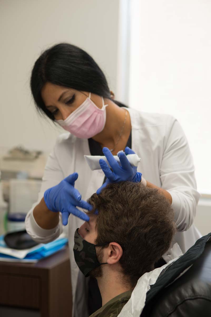 Technician preparing female patient for prp platelet rich plasma vampire facelift